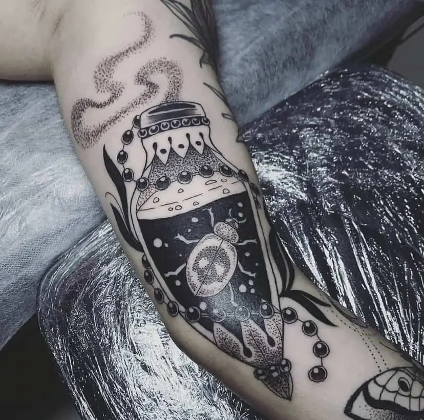 Black and white beetle in glass jar arm tattoo