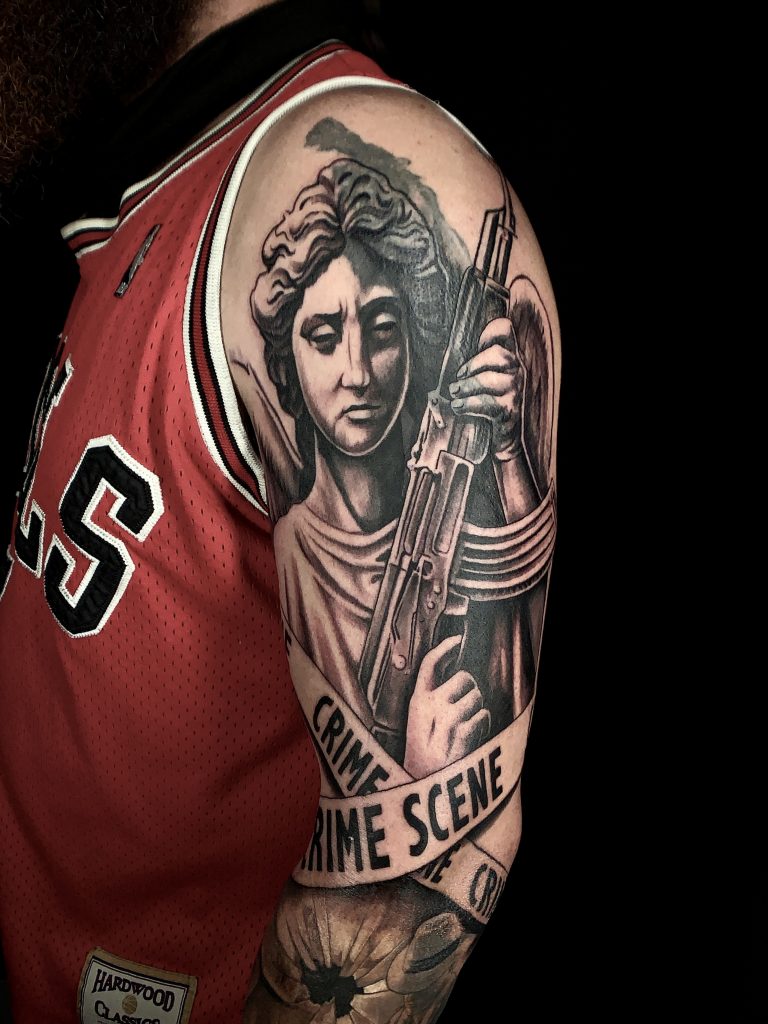 Man with black and white angel with gun sleeve tattoo